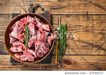 Fresh Raw meat on the bone diced for goulash in a wooden plate. Wooden background. Top View. Copy space 87490237