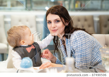 a beautiful dark-haired woman with a one-year-old boy at the banquet.  87490506