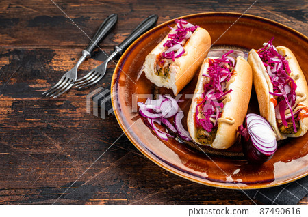 Street food - Vegan hot-dogs with cabbage and meatless sausage. Dark Wooden background. Top view. Copy space Street food - Vegan hot-dogs with cabbage and meatless sausage. Dark Wooden background. Top view. Copy space 87490616