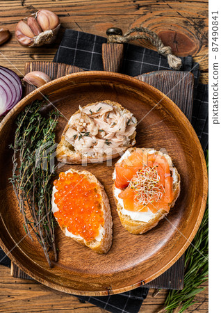 Bruschetta with Hot Smoked salmon, red caviar and herbs. Wooden background. Top view Bruschetta with Hot Smoked salmon, red caviar and herbs. Wooden background. Top view 87490841