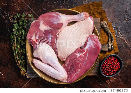 Fresh duck meat parts, raw breast steak, legs, wings in a plate with herbs. Dark background. Top view Fresh duck meat parts, raw breast steak, legs, wings in a plate with herbs. Dark background. Top view 87490873