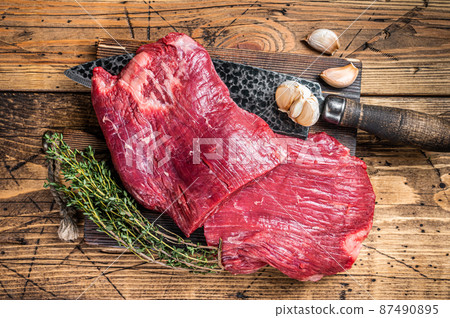 Flank raw beef steaks on a butcher cutting board with knife. wooden background. Top view 87490895