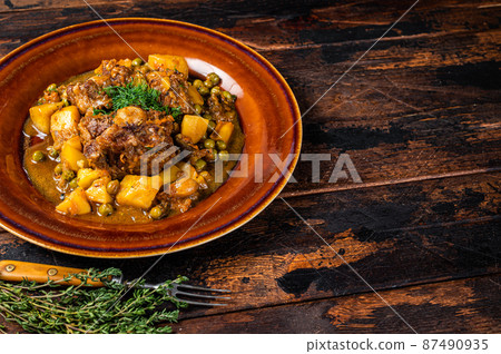 Beef veal oxtails stew with vegetables in a rustic plate. Dark wooden background. Top view. Copy space 87490935