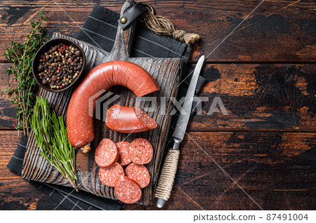 Sliced Sucuk beef meat sausage on a cutting board with herbs. Wooden background. Top view. Copy space Sliced Sucuk beef meat sausage on a cutting board with herbs. Wooden background. Top view. Copy space 87491004