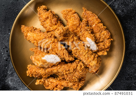 Breaded chicken strips, breast fillet meat on a plate. Black backgrund. Top view 87491031
