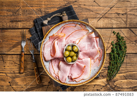Smoked Ham slices in plate with olives. Wooden background. Top view 87491083