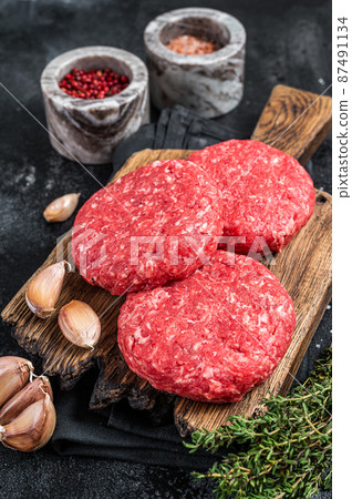 Raw veal hamburger patties with herbs and spices. Black background. Top view 87491134