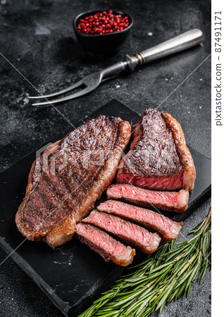 Grilled top sirloin or cup rump beef meat steak on marble board. Black background. Top view 87491171