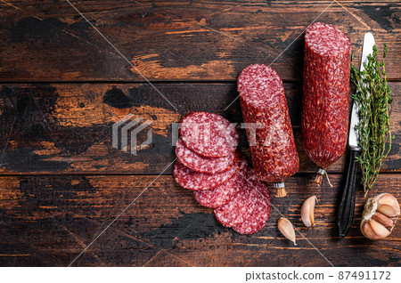 Sliced salami cured sausage on kitchen table. Wooden background. Top view. Copy space 87491172