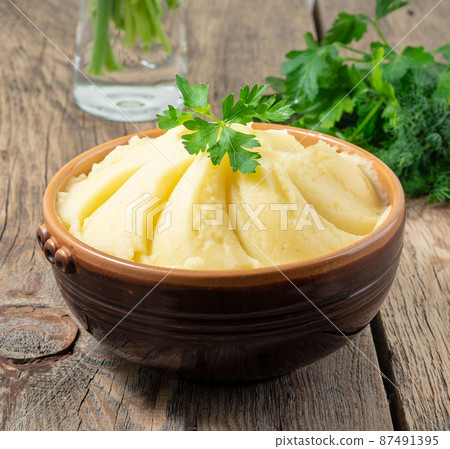 Mashed potatoes, boiled puree in brown bowl on dark wooden rustic background, side view Mashed potatoes, boiled puree in brown bowl on dark wooden rustic background, side view 87491395