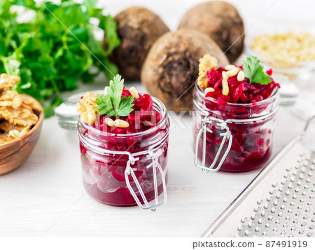 Fresh salad of grated boiled beetroot in glass jars, white wooden background, side view. Fresh salad of grated boiled beetroot in glass jars, white wooden background, side view. 87491919