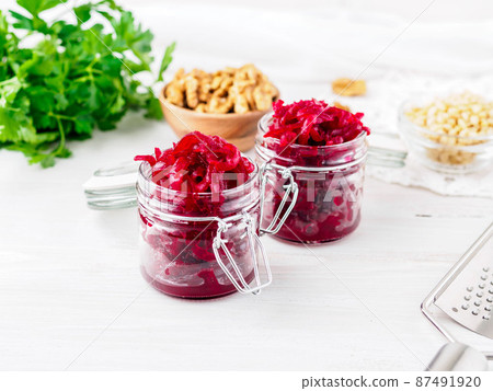 Fresh salad of grated boiled beetroot in jars, white wooden background, side view. Fresh salad of grated boiled beetroot in jars, white wooden background, side view. 87491920