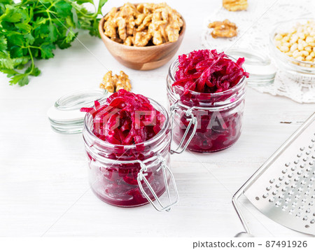 Fresh salad of grated boiled beetroot in jars, white wooden background, side view. Fresh salad of grated boiled beetroot in jars, white wooden background, side view. 87491926
