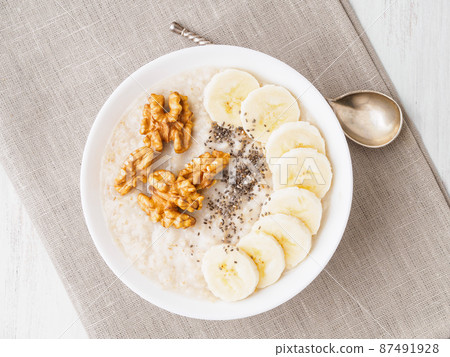 healthy breakfast - oatmeal with nuts, bananas, chia, top view healthy breakfast - oatmeal with nuts, bananas, chia, top view 87491928