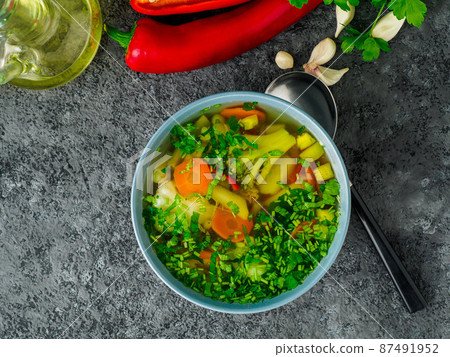 Healthy spring vegetable dietary vegetarian soup, gray dark concrete background, top view, close up. Healthy spring vegetable dietary vegetarian soup, gray dark concrete background, top view, close up. 87491952