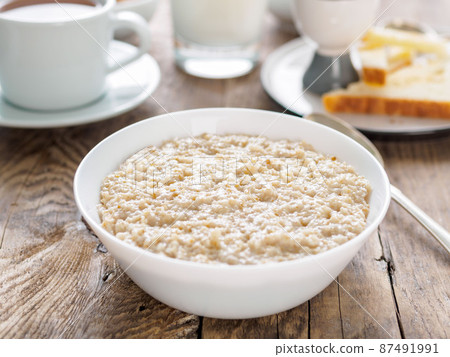 Large bowl of tasty and healthy oatmeal for Breakfast, morning meal. Side view, close up, wooden rustic table. Large bowl of tasty and healthy oatmeal for Breakfast, morning meal. Side view, close up, wooden rustic table. 87491991