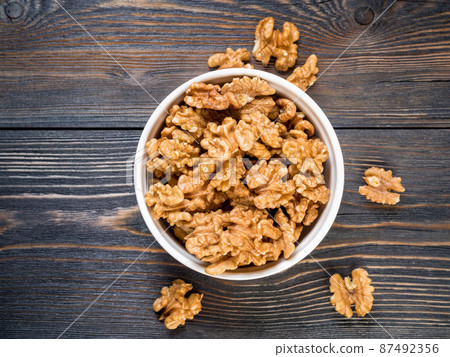 Top view of glass jar with a handful of walnut, circassian nuts on a wooden dark background. Top view of glass jar with a handful of walnut, circassian nuts on a wooden dark background. 87492356