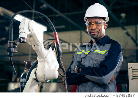 African American factory worker working with adept robotic arm 87492887