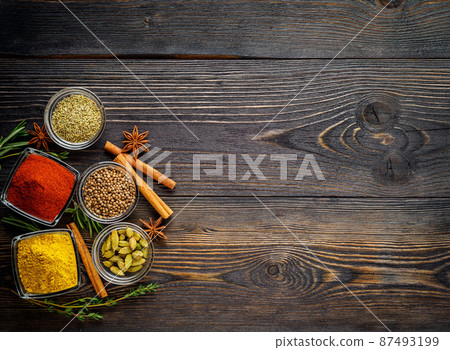 Set of spices and herbs on dark brown textured wooden table. Top view, empty space 87493199