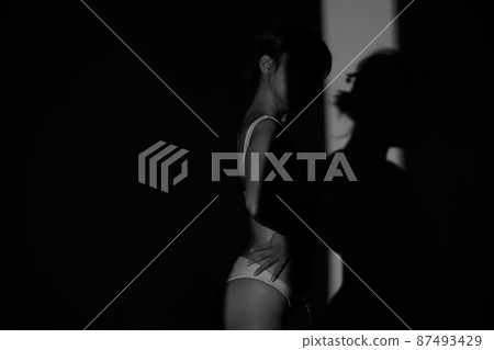 Half body Asian Woman 20s wear Bikini stay in shade of shadow from sunset window curtain 87493429