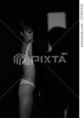 Half body Asian Woman 20s wear Bikini stay in shade of shadow from sunset window curtain 87493430