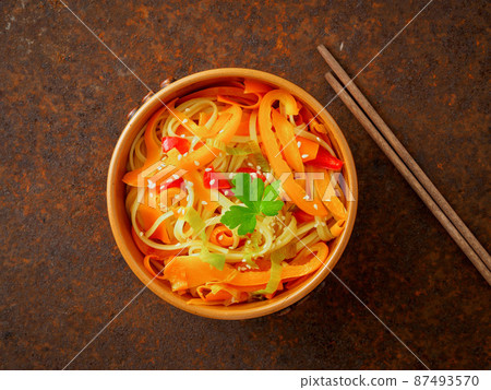 Asian cuisine, noodles stir-fry udon with vegetables. Pepper, carrot, leek, sesame on a brown metal dark table, top view Asian cuisine, noodles stir-fry udon with vegetables. Pepper, carrot, leek, sesame on a brown metal dark table, top view 87493570