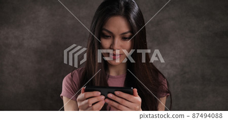 Asian woman watches a video on her phone 87494088