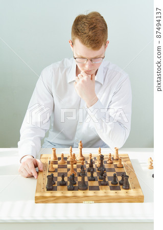 Quarantine, self-isolation. Home games, Smart guy is playing chess Quarantine, self-isolation. Home games, Smart guy is playing chess 87494137