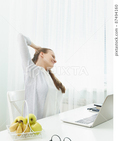 Woman stretches her arms, kneads her back from fatigue. Long sitting at computer, muscle cramps. 87494160