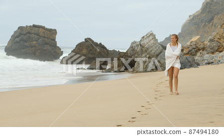 Walk along a sandy beach at the Ocean - Young woman on summer holiday 87494180