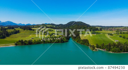 Aerial view over Lake Forggensee at the city of Fuessen in Germany  87494230