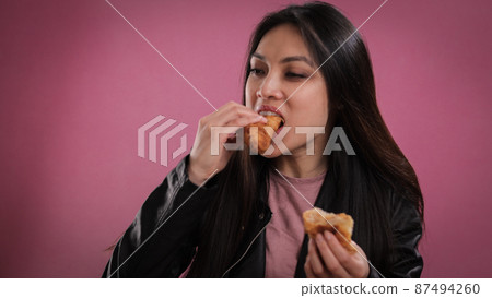 Young woman eats a freshly baked croissant 87494260