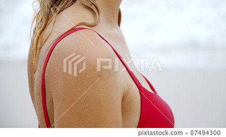 Sexy woman in a bikini relaxes on a sandy beach at the ocean Sexy woman in a bikini relaxes on a sandy beach at the ocean 87494300