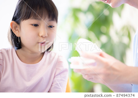 Girl receiving tooth brushing instruction from a dentist 87494374