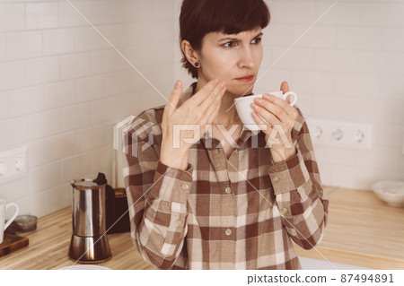 COVID-19 causes loss of smell. Woman sniffing smell of coffee from cup while preparing drink COVID-19 causes loss of smell. Woman sniffing smell of coffee from cup while preparing drink 87494891