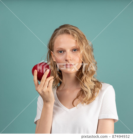 Beautiful young serious clever blonde woman without makeup with red apple Beautiful young serious clever blonde woman without makeup with red apple 87494932