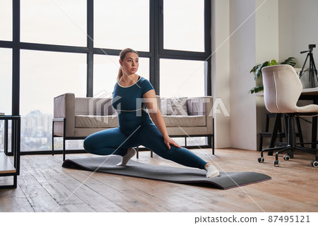 Concentrated expectant woman with amputee arm practicing yoga and stretching 87495121