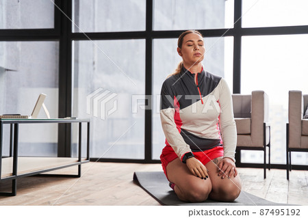Woman with prosthesis arm sitting at the floor with closed eyes and relaxing 87495192