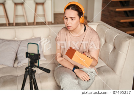 Modern smartphone gadget on tripod recording young female speaker or coach with amputee arm 87495237