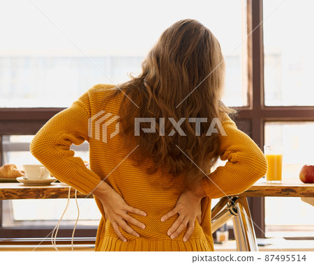 Back view of faceless young woman touching back feeling backache, discomfort 87495514