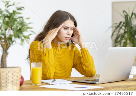 Woman massaging temples of head due to headache from long work 87495517