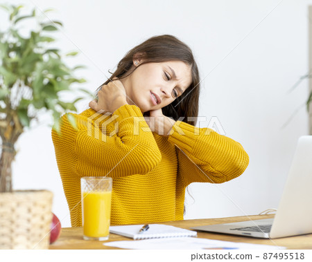 Woman massaging neck pain from working at computer for long time 87495518
