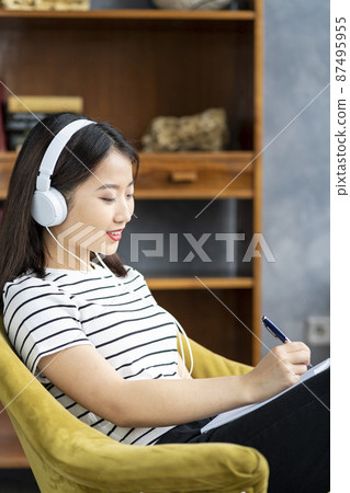 Asian Woman writing in notebook, planning day in diary. Beautiful business female Asian Woman writing in notebook, planning day in diary. Beautiful business female 87495955