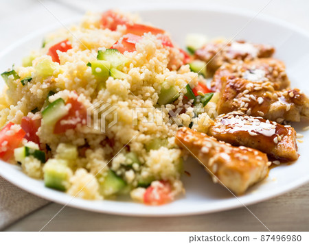 Turkey meat, fried, with teriyaki sauce and sesame seeds. A side dish of Couscous with vegetables. Selective focus, day natural light 87496980