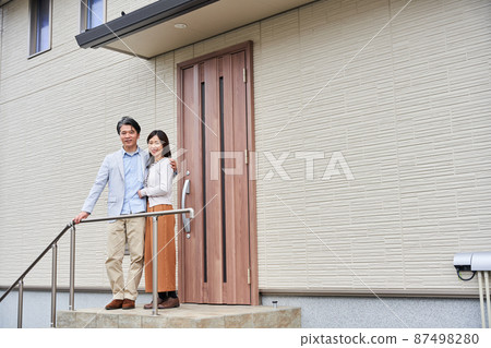 A couple standing in front of their home 87498280