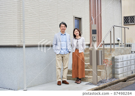 A couple standing in front of their home A couple standing in front of their home 87498284