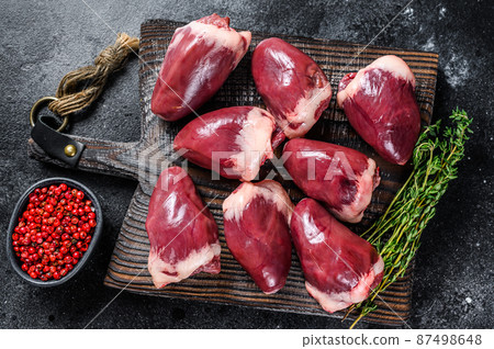 Raw turkey hearts offal with herbs and spices. Black background. Top view 87498648