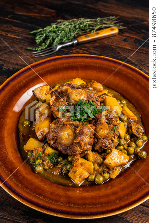 Beef veal oxtails stew with vegetables in a rustic plate. Dark wooden background. Top view 87498650