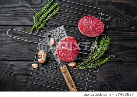 Grill BBQ - Raw Fillet Mignon beef steaks with herbs. Black wooden background. Top view 87498657
