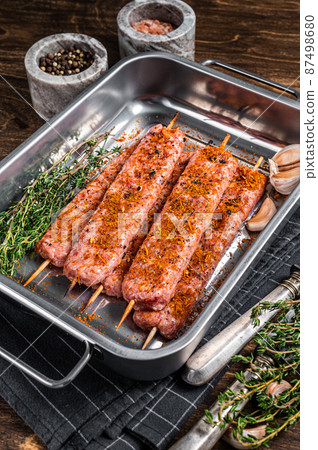 Raw Urfa shish kebab in butcher tray with herbs. Wooden background. top view Raw Urfa shish kebab in butcher tray with herbs. Wooden background. top view 87498680